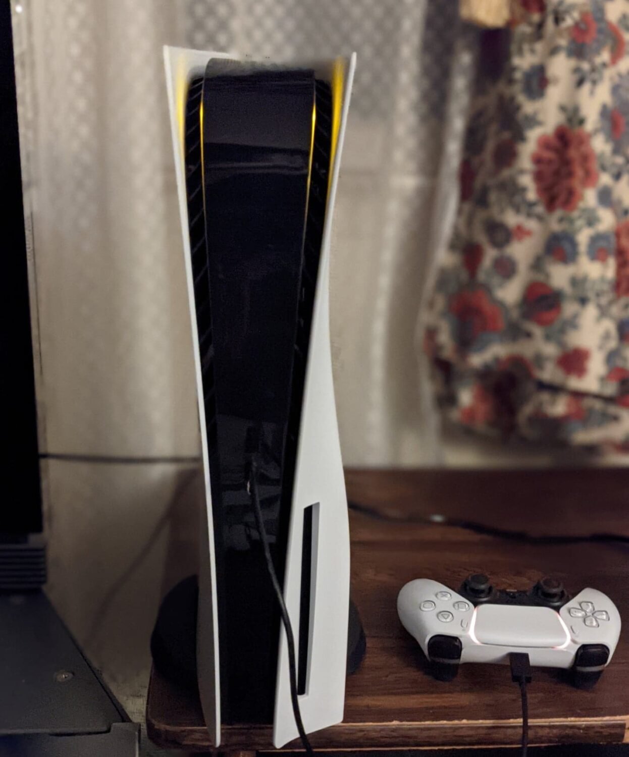 PlayStation 5 console standing vertically next to a charging DualSense controller