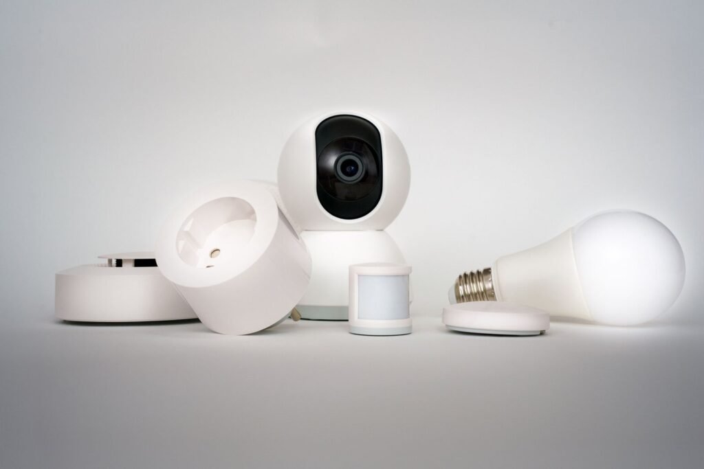 A small smart home camera and connected sensors arranged on a surface in a minimalist home setup