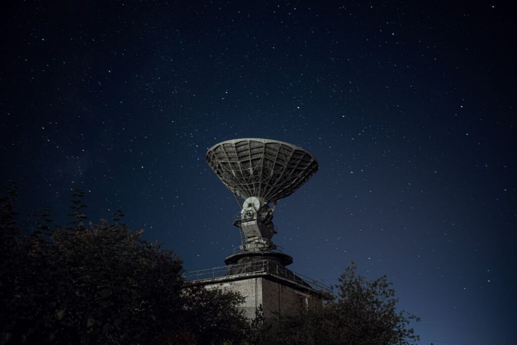 Large satellite antenna silhouetted against a star filled night sky, representing Starlink Mobile's satellite layer