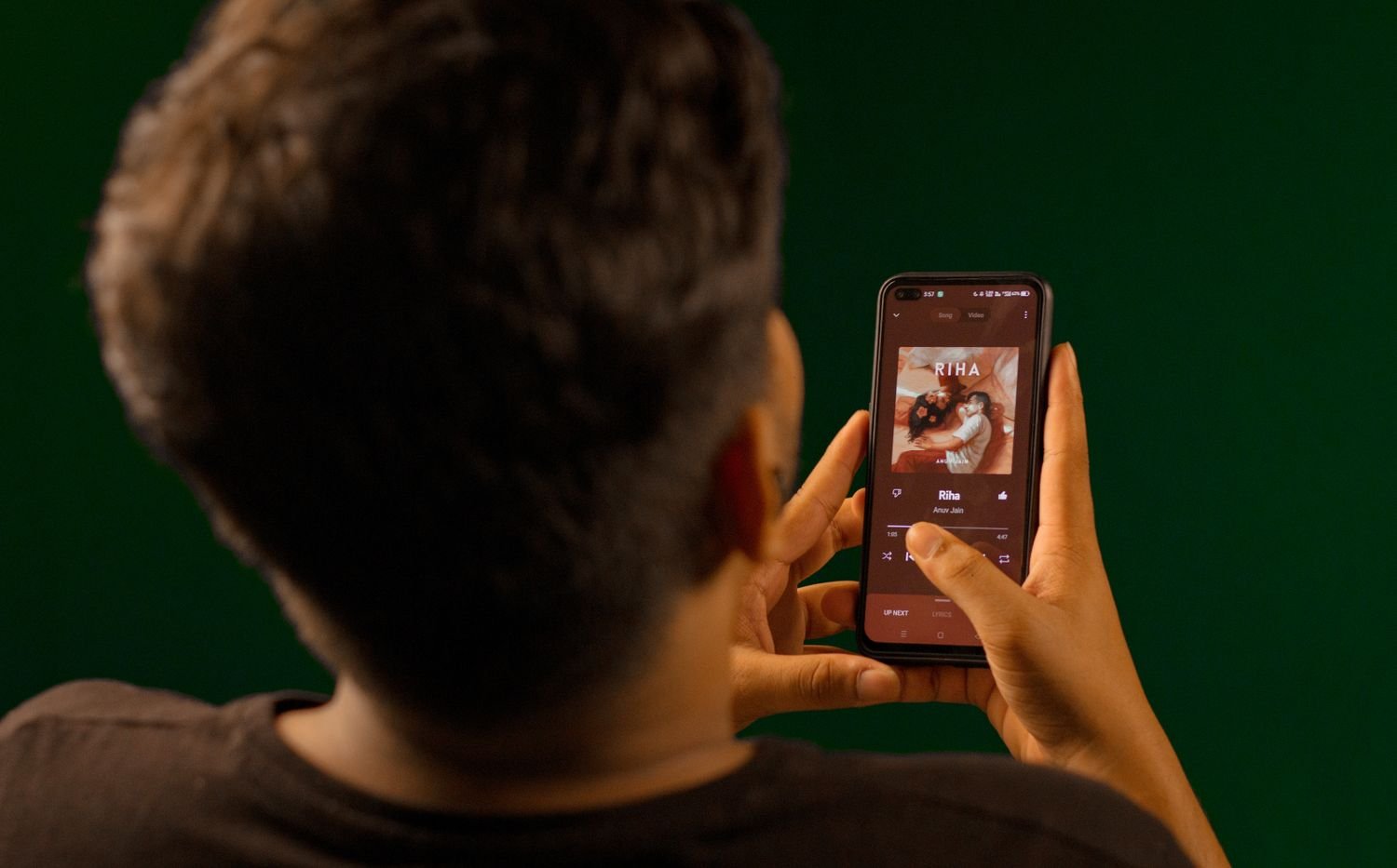 Man seen from behind streaming a song on his smartphone