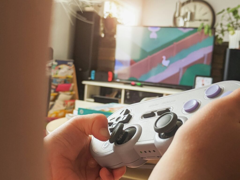 Person holding a white Xbox controller while playing a game on a TV